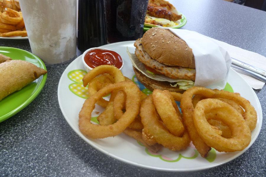 Onion rings are the perfect fat-filled side to counteract the lean turkey burger with tomato and lettuce on a whole wheat bun.