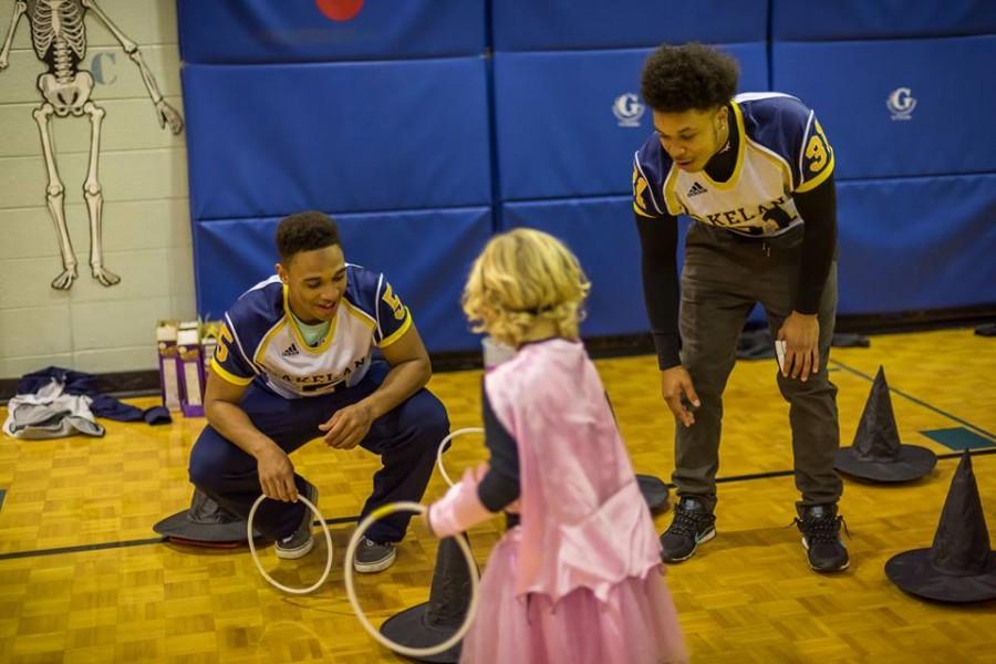 Sophomore Michael Whitley (left) and Freshman Eddie Strickland (right) cheer on a child at Lincoln-Erdman Elementary Schools Halloween event.