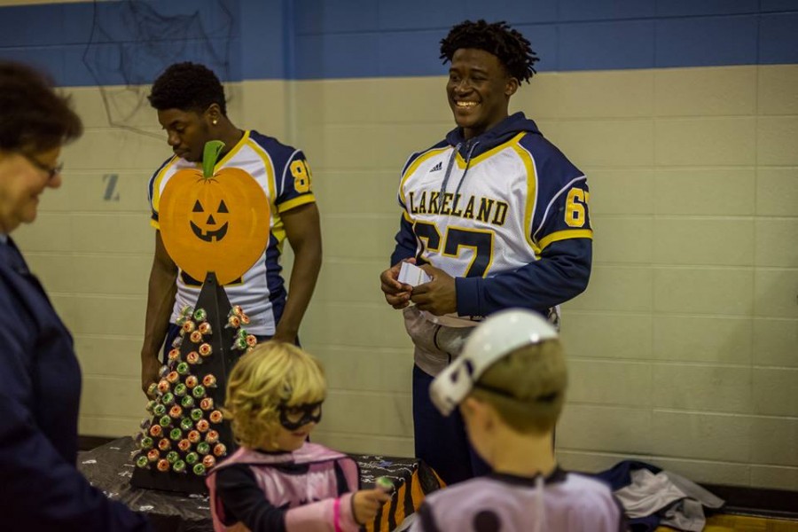 Freshman Jamal Hawkins-Sconiers (left) and freshman Washington Vivanco (right) greet guests and hand out candy at Lincoln-Erdman Elementary Schools Halloween event.